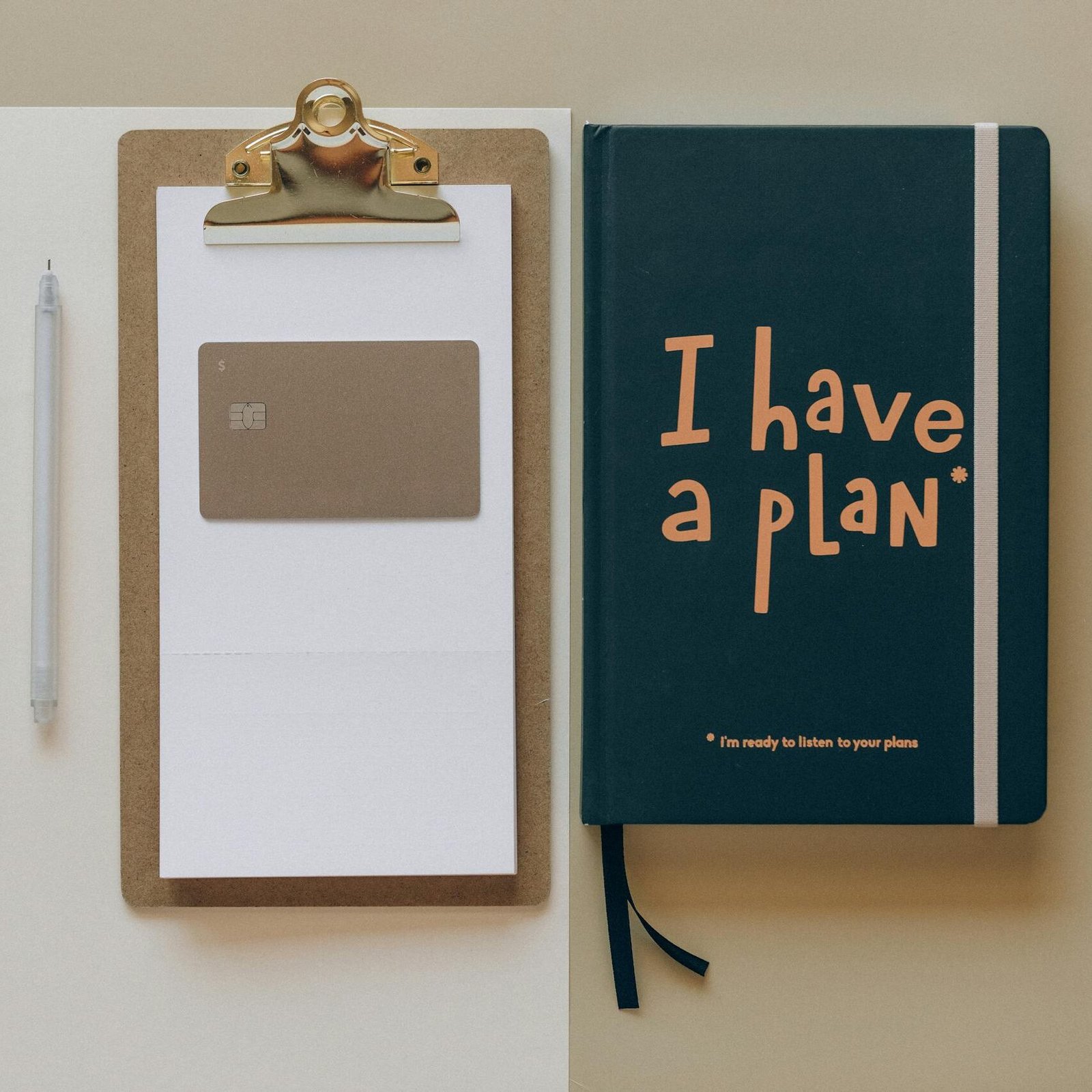 A minimalist office setup featuring a planner, clipboard, card, and pen, perfect for planning and organization.