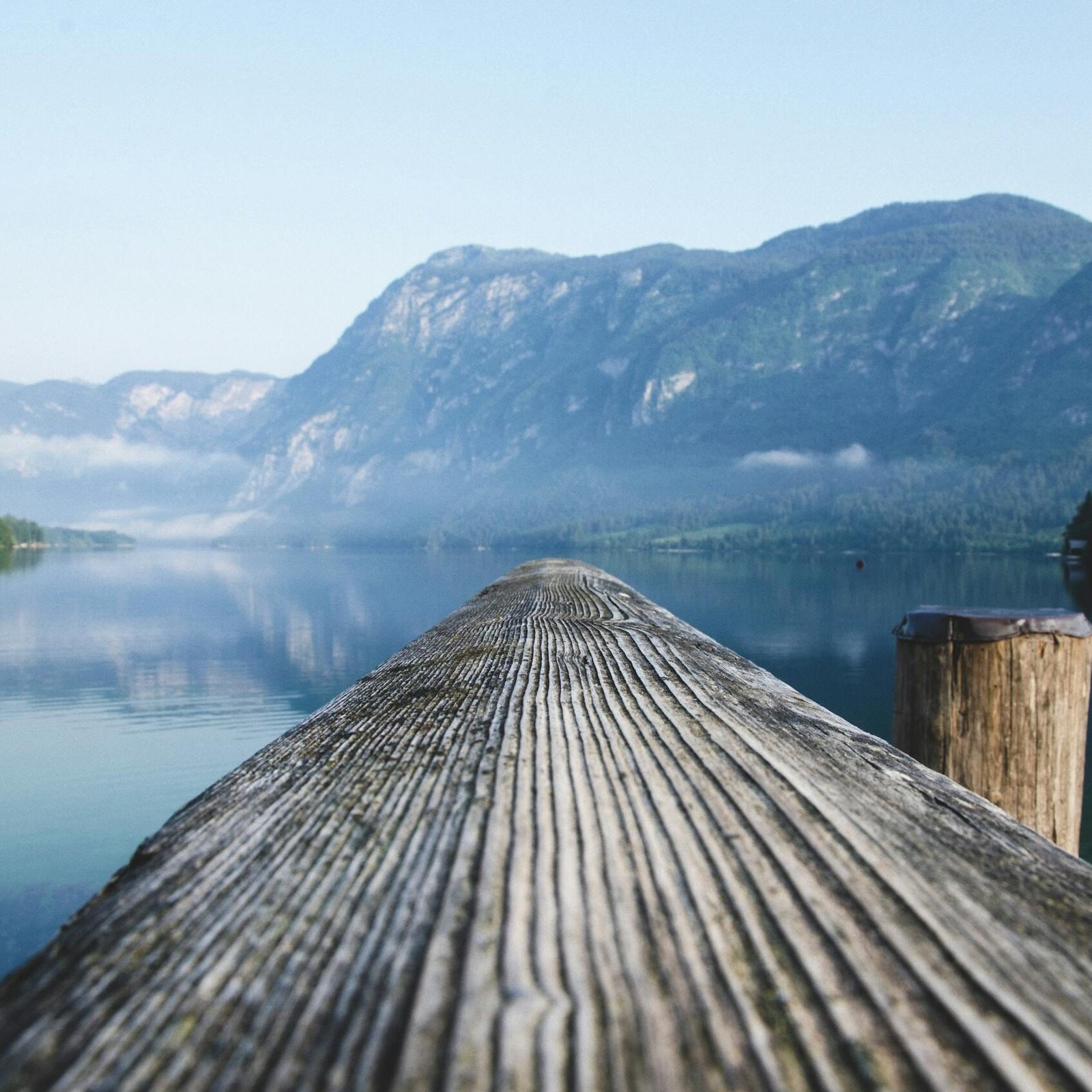 Serene view of a mountain lake from a wooden dock in Radovljica, Slovenia.